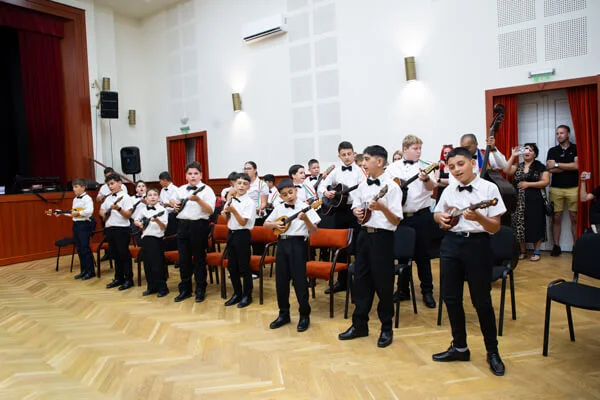 A gyermekzenekar tagjai állva, egy sorban játszanak tamburán és gitáron a Csokonai Rendezvényházban.