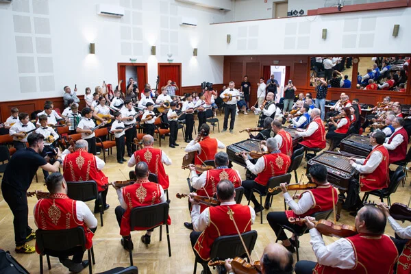 A SUGO Tamburazenekar és a 100 Tagú Cigányzenekar egymással szemben ülve muzsikál a próbateremben.