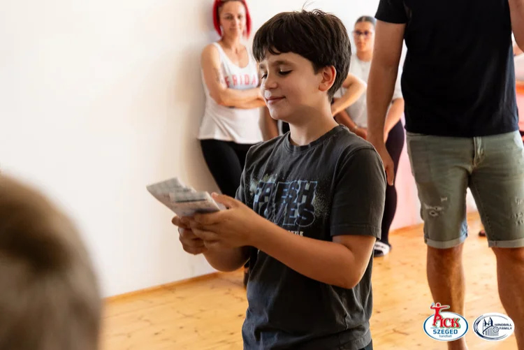Fiú mosolyogva nézi a kezében tartott PICK Szeged autogramkártyát a sükösdi találkozó során