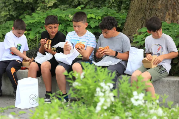 Öt fiú hamburgert eszik a parkban az Országgyűlés alakuló ülésén tartott fellépés előtt.